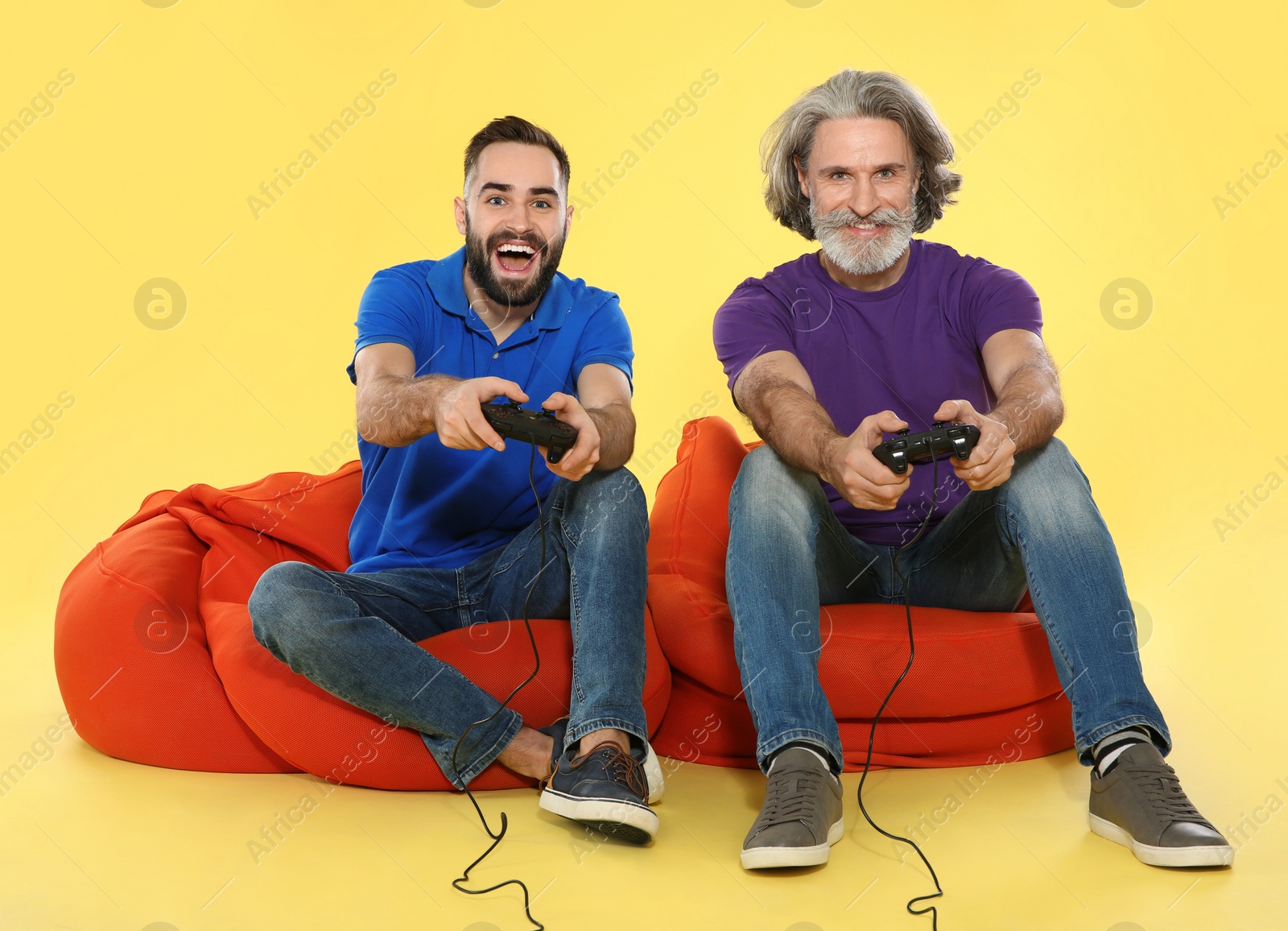 Photo of Mature man and guy playing video games with controllers on color background