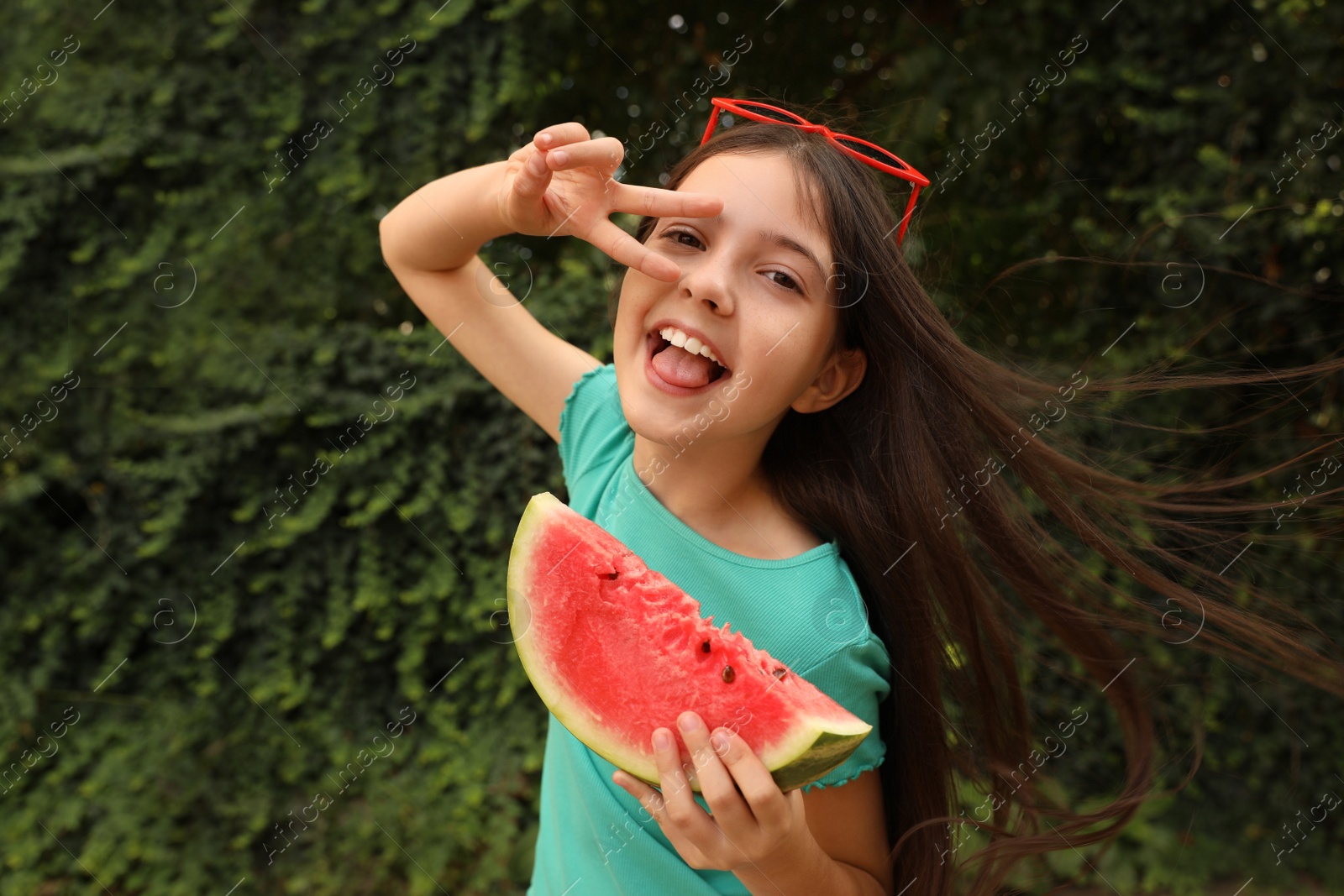 Photo of Cute little girl with watermelon outdoors on sunny day