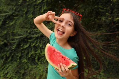 Photo of Cute little girl with watermelon outdoors on sunny day