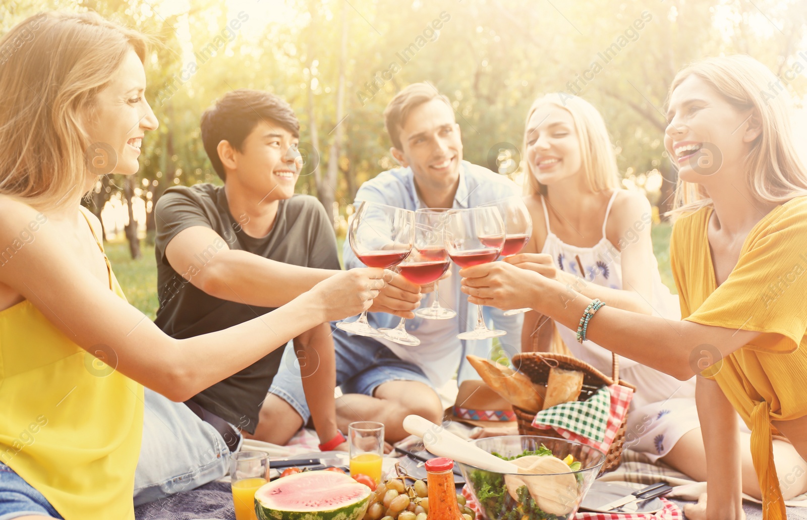 Image of Happy friends having picnic in park on sunny day