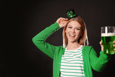 Photo of Young woman with green beer on black background. St. Patrick's Day celebration