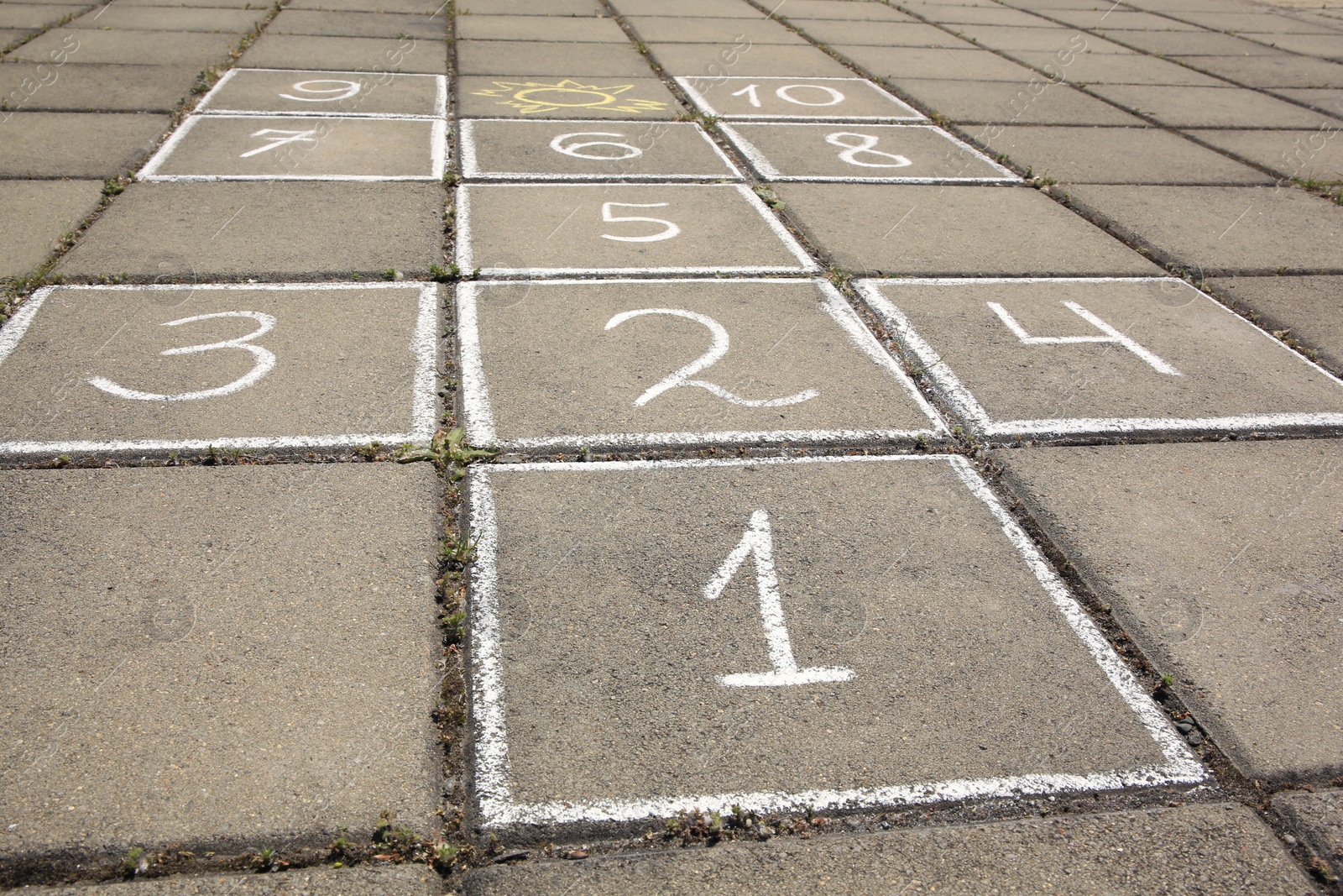 Photo of Hopscotch drawn with white chalk on street tiles outdoors