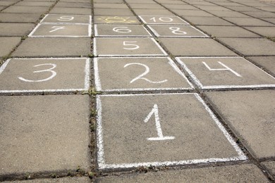 Hopscotch drawn with white chalk on street tiles outdoors