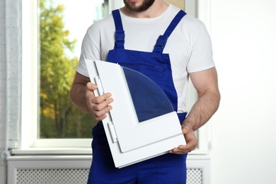 Photo of Installation worker with sample of modern window profile indoors