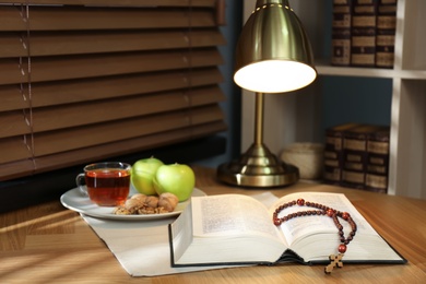 Holy Bible with prayer beads and snacks on wooden table indoors. Great Lent season