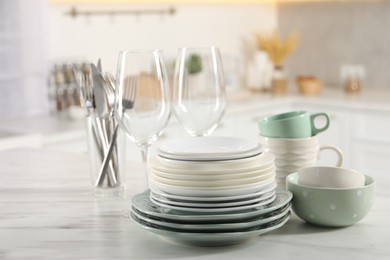 Photo of Many different clean dishware and glasses on white marble table in kitchen. Space for text