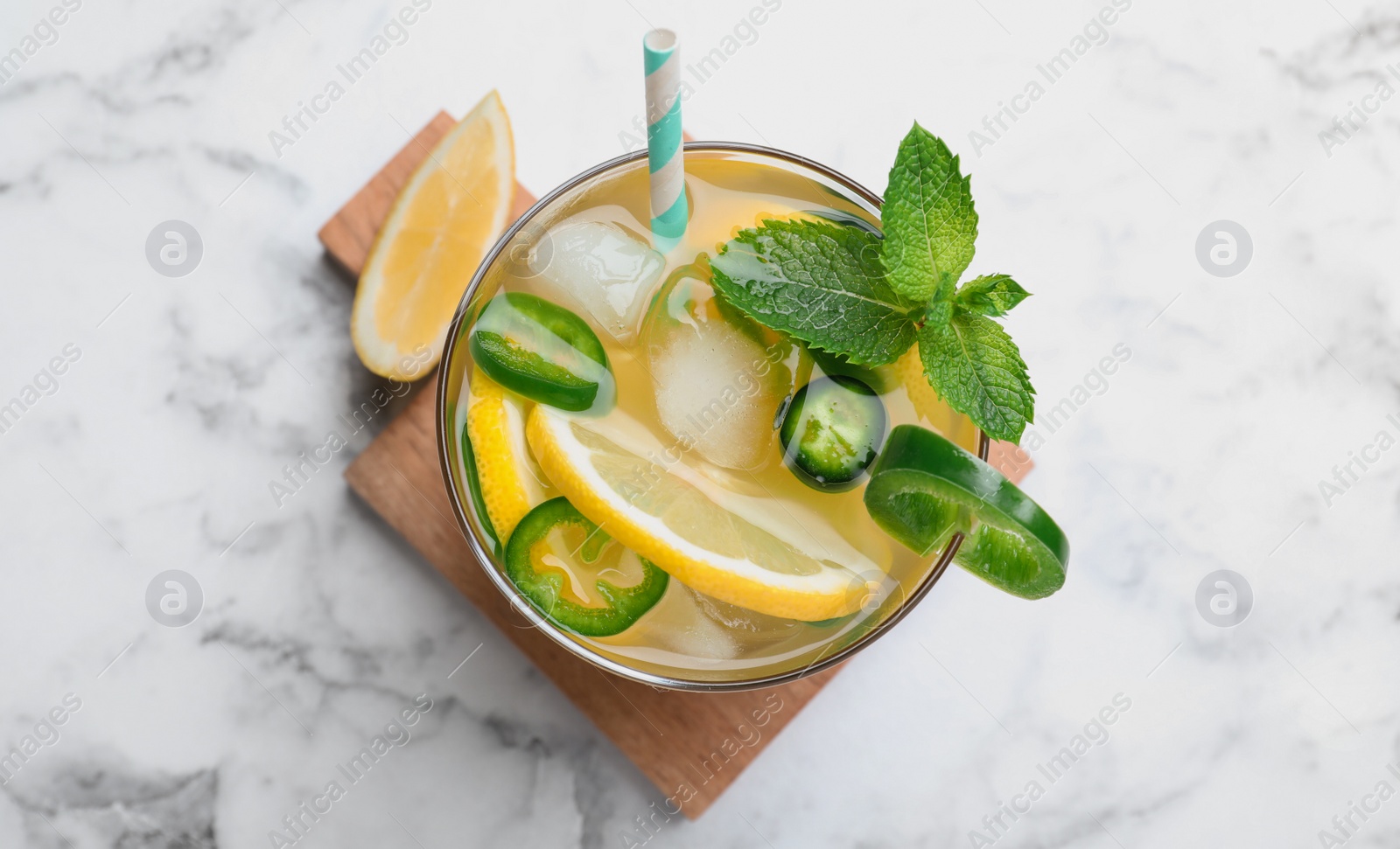 Photo of Spicy cocktail with jalapeno, lemon and mint on white marble table, top view