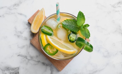 Spicy cocktail with jalapeno, lemon and mint on white marble table, top view