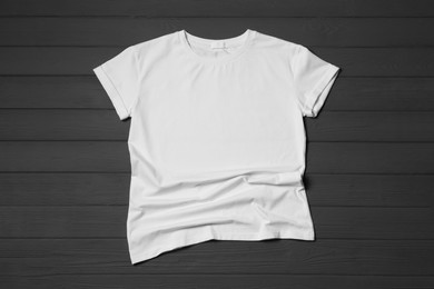 Stylish white T-shirt on gray wooden table, top view