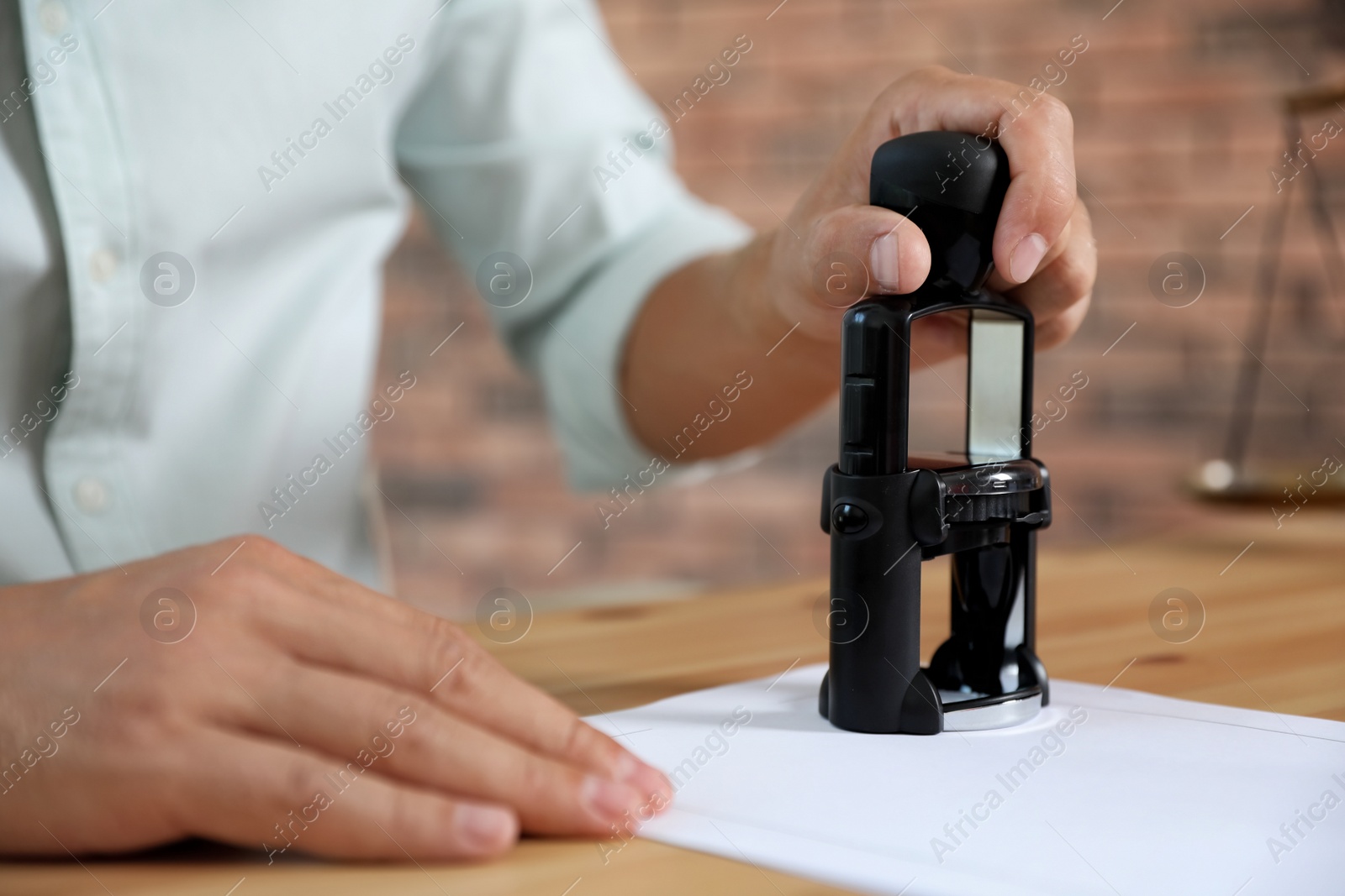 Photo of Male notary stamping document at table, closeup