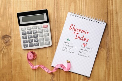 List with products of low and high glycemic index in notebook, calculator and measuring tape on wooden table, flat lay