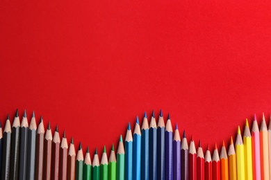 Photo of Flat lay composition with color pencils on red background. Space for text