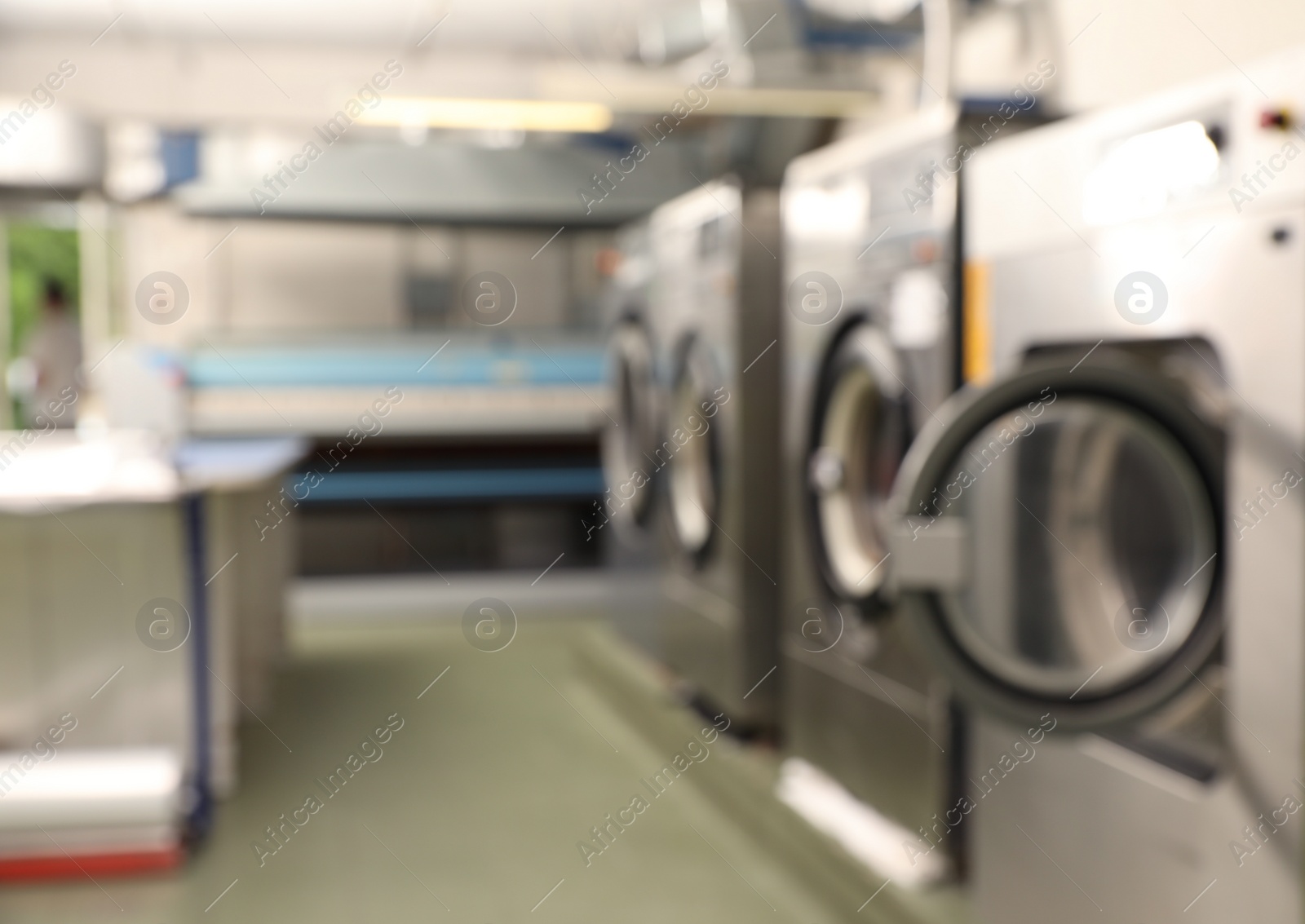 Photo of Blurred view of dry-cleaning equipment indoors. Space for text