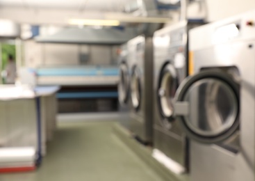 Blurred view of dry-cleaning equipment indoors. Space for text