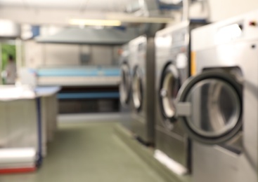 Photo of Blurred view of dry-cleaning equipment indoors. Space for text