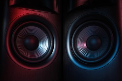 Photo of Modern sound speakers in neon light as background, closeup