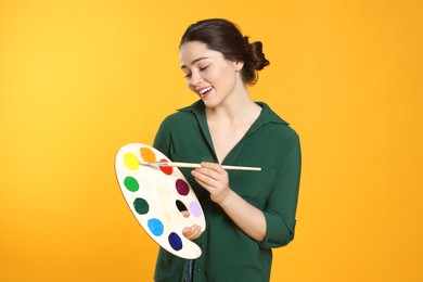 Photo of Woman with painting tools on yellow background. Young artist