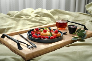 Tasty breakfast served in bedroom. Cottage cheese pancakes with fresh berries and mint on wooden tray