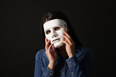 Multiple personality concept. Woman in mask on black background