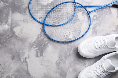 Badminton rackets and shoes on white marble table, flat lay. Space for text