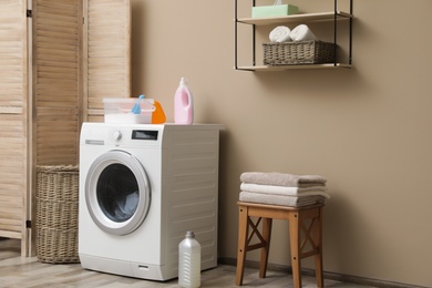 Modern washing machine near color wall in laundry room interior. Space for text