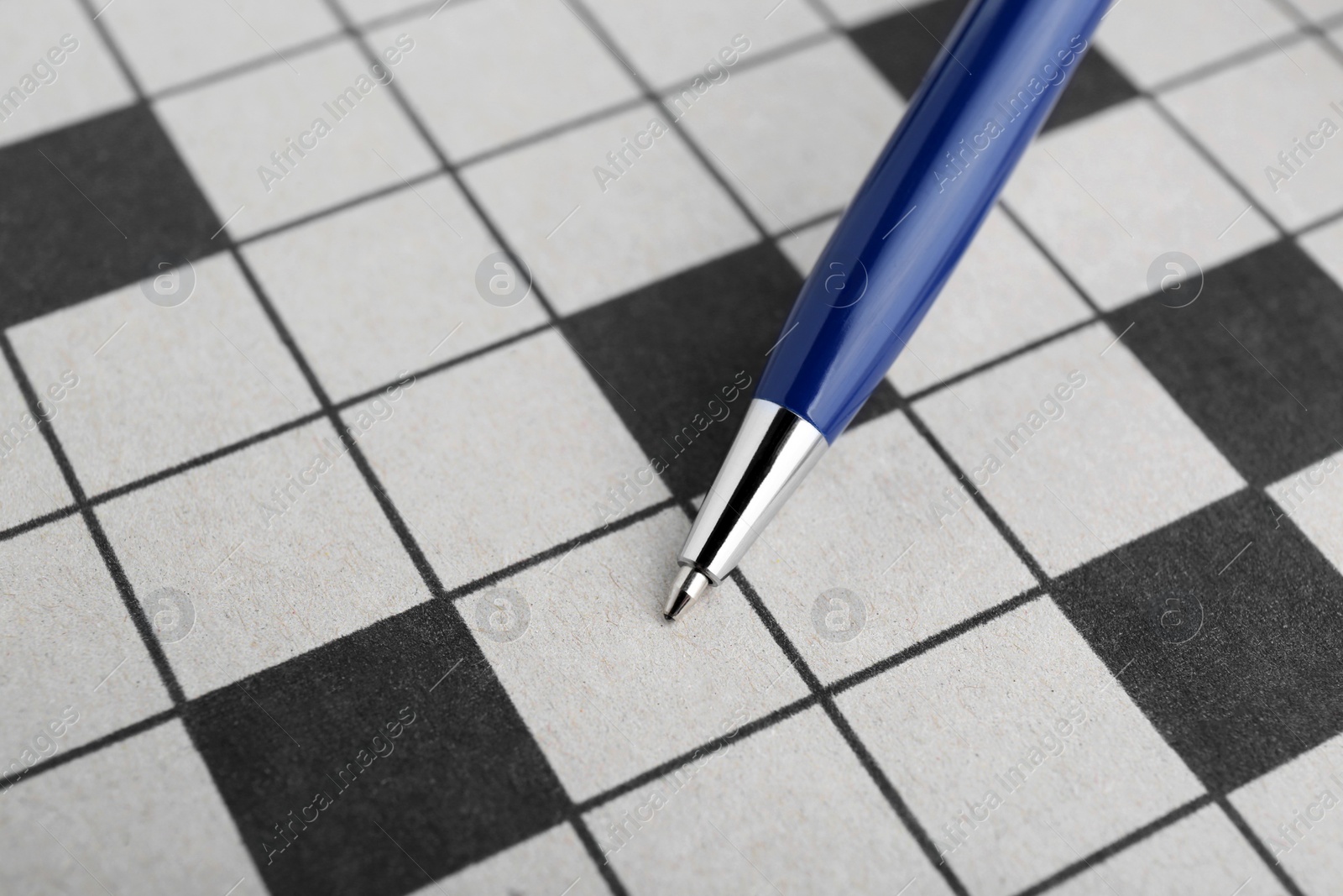 Photo of Pen on blank crossword, closeup. Intellectual entertainment