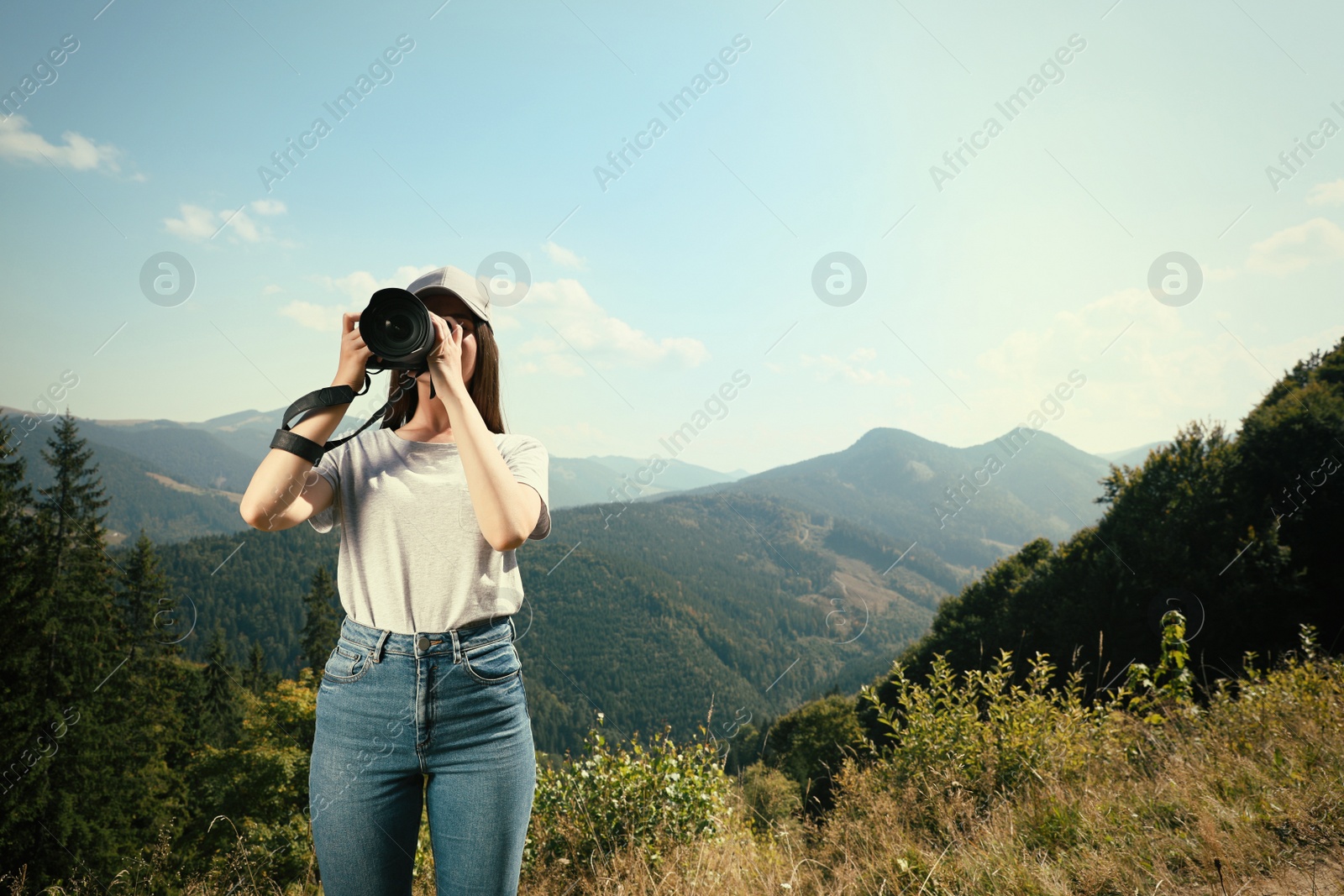 Photo of Professional photographer taking picture with modern camera in mountains. Space for text