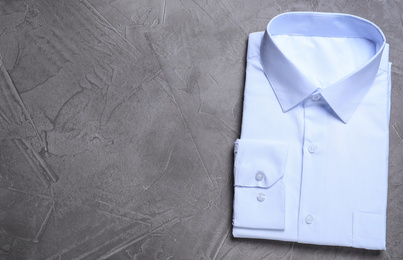 Photo of Stylish white shirt on grey stone background, top view with space for text. Dry-cleaning service