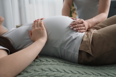 Photo of Doula taking care of pregnant woman indoors, closeup. Preparation for child birth