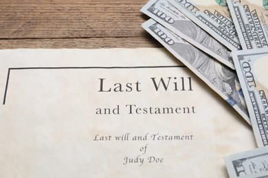 Photo of Last Will and Testament with dollar bills on wooden table, closeup