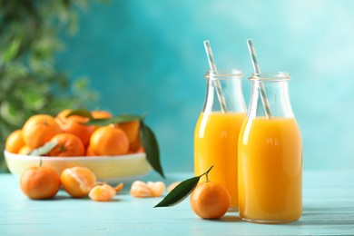 Photo of Bottles of fresh tangerine juice on blue wooden background. Space for text