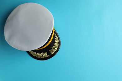 Peaked cap with accessories on light blue background, top view. Space for text
