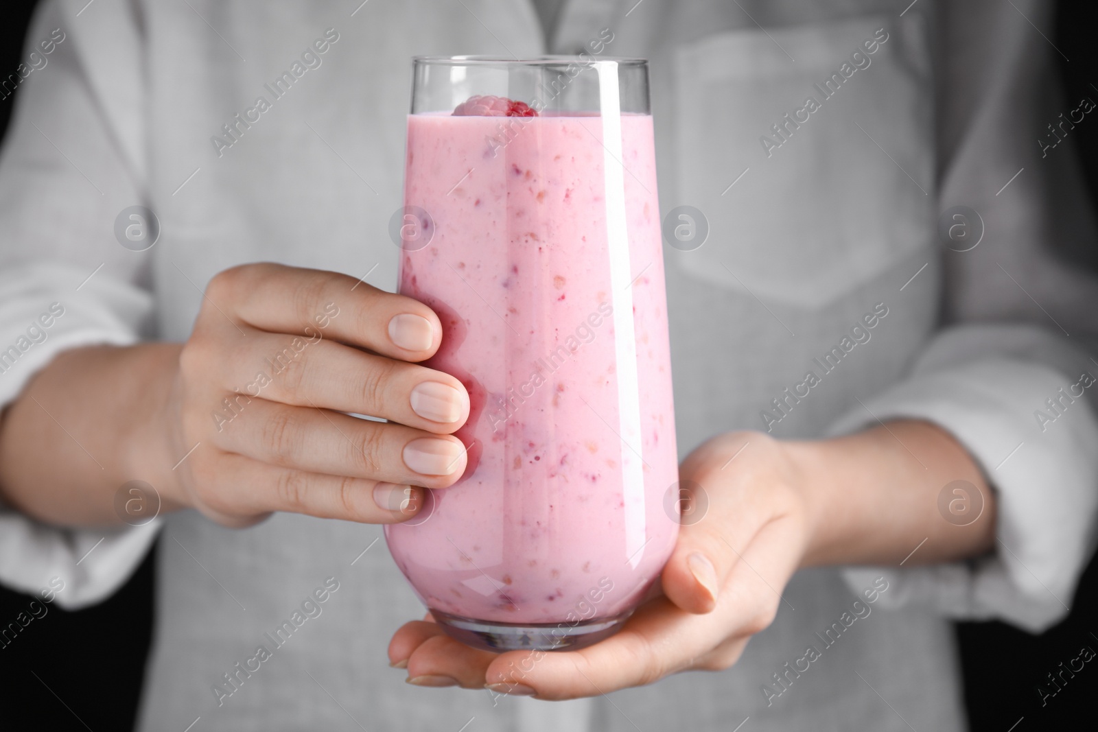 Photo of Woman holding glass of tasty raspberry smoothie, closeup