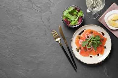 Delicious salmon carpaccio served on black table, flat lay. Space for text