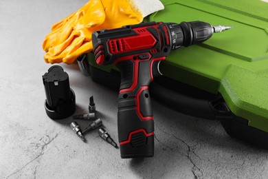 Photo of Electric screwdriver, case, drill bits, battery and gloves on light table