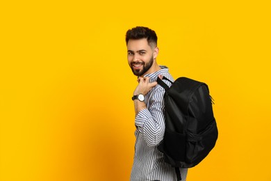 Photo of Young man with stylish backpack on yellow background. Space for text