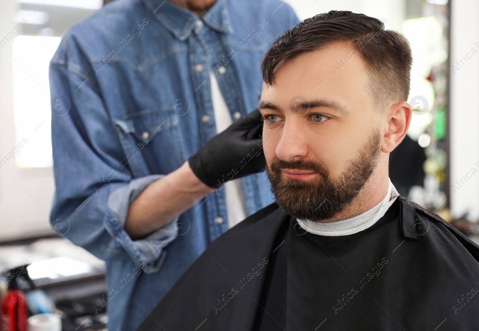 Photo of Professional barber working with client in hairdressing salon. Hipster fashion