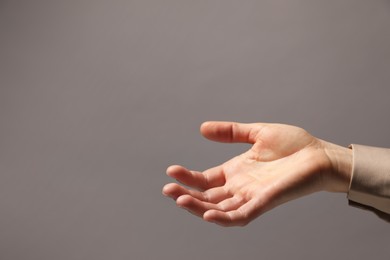 Woman holding something in hand on grey background, closeup. Space for text