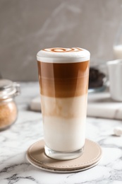 Photo of Glass with delicious caramel latte on table