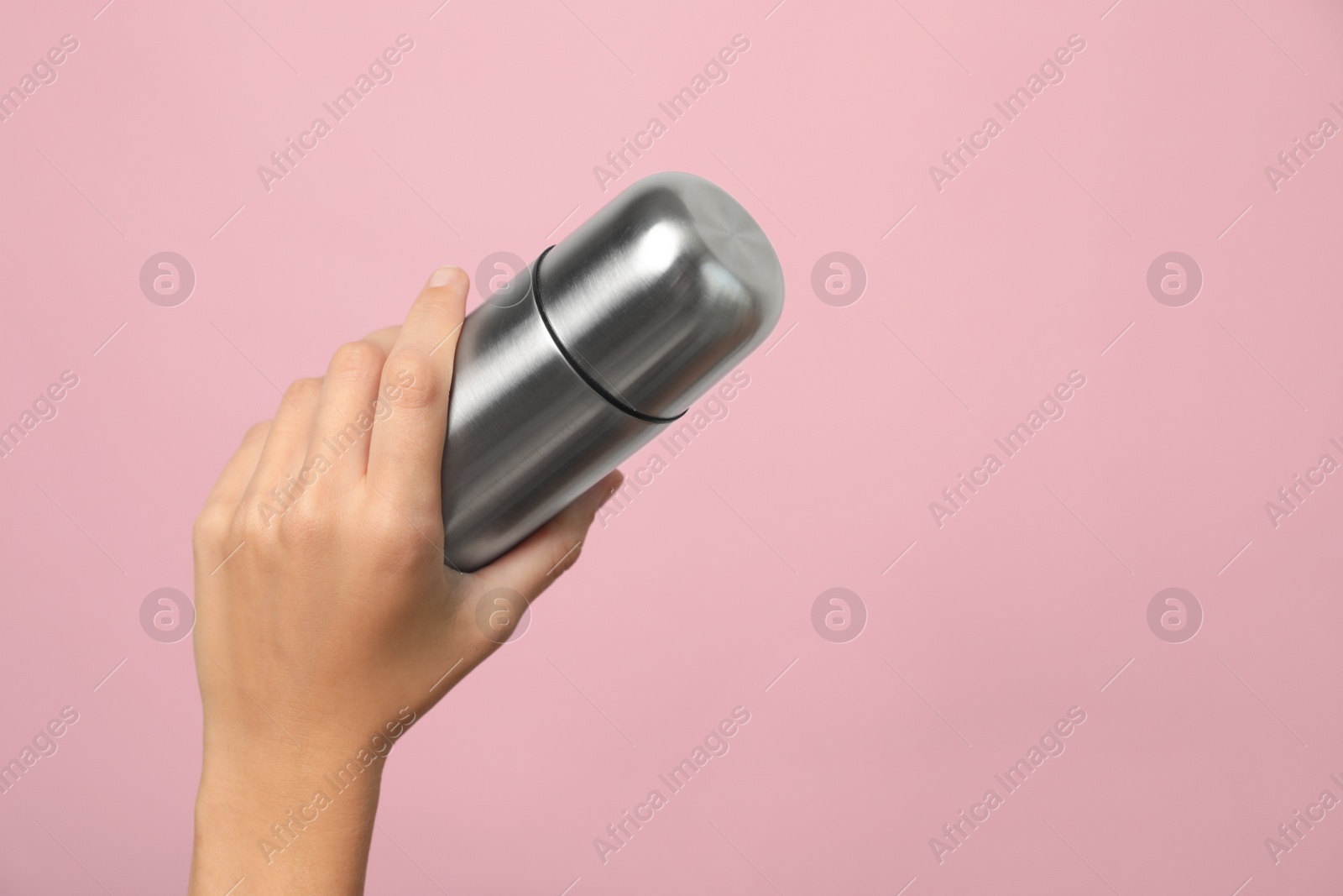 Photo of Woman holding modern thermos on pink background, closeup. Space for text