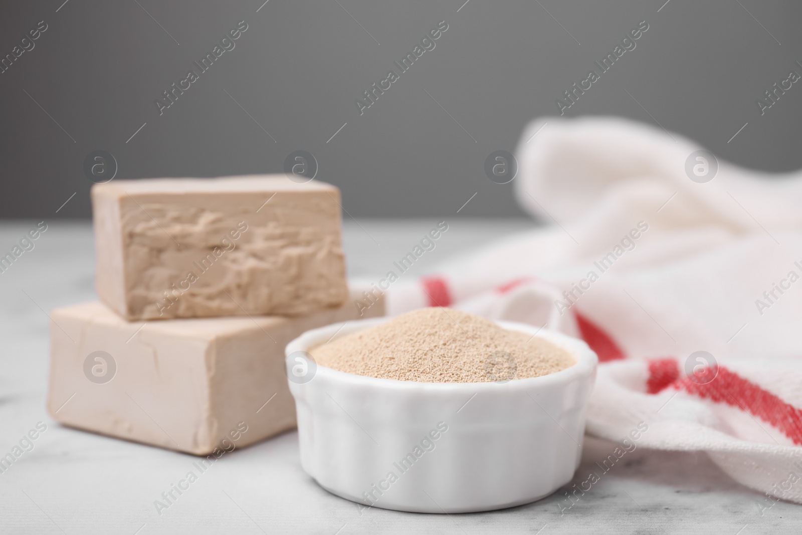 Photo of Granulated and compressed yeast on white marble table, closeup