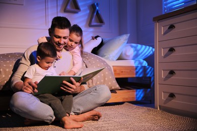 Photo of Father reading bedtime story to his children at home