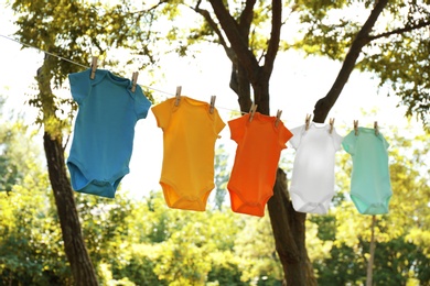 Photo of Colorful baby onesies hanging on clothes line outside