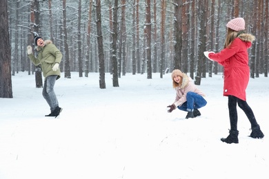 Happy family playing snowballs in winter forest