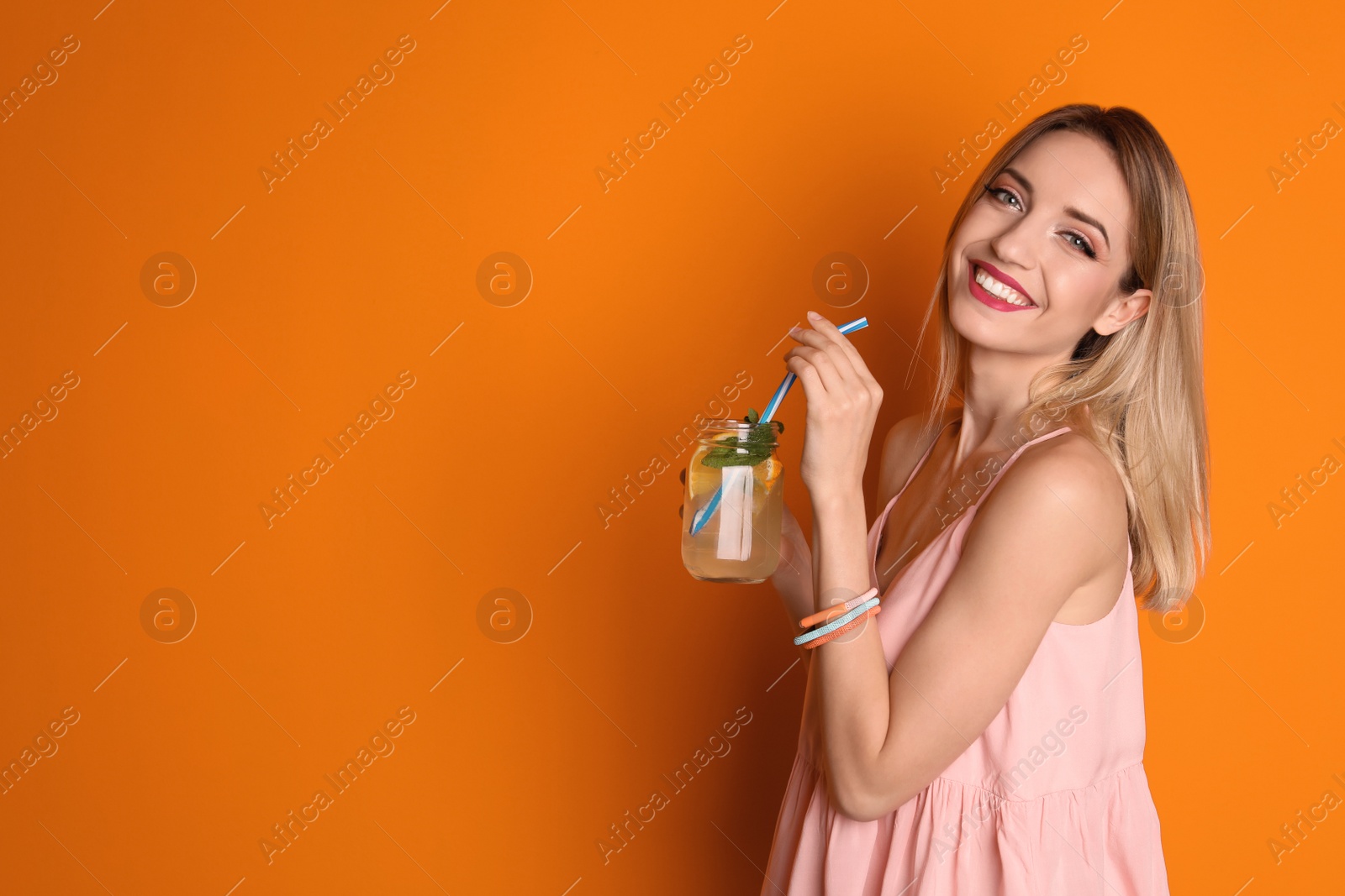 Photo of Young woman with mason jar of tasty lemonade on color background. Natural detox drink