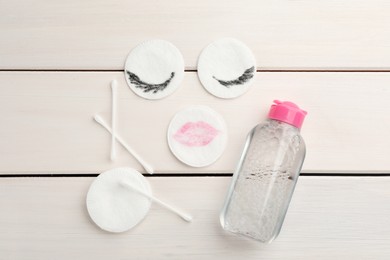 Dirty cotton pads, swabs and micellar cleansing water on white wooden background, flat lay