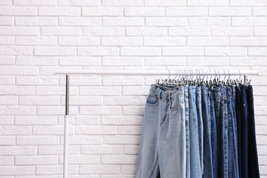 Photo of Rack with stylish jeans near brick wall