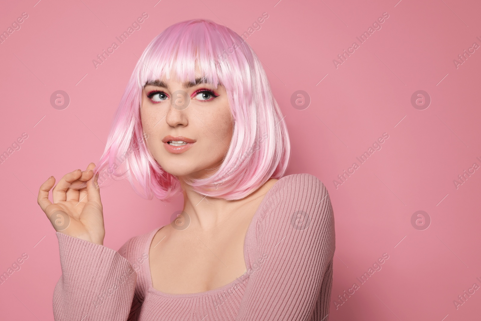 Photo of Beautiful woman with bright makeup and fake freckles on pink background