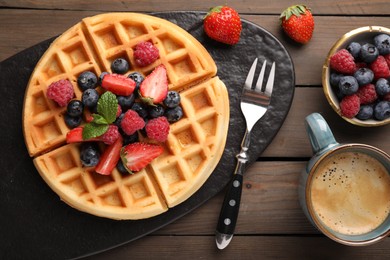 Photo of Tasty Belgian waffle with fresh berries served on wooden table, flat lay
