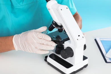 Photo of Male doctor using microscope at table, closeup. Medical object